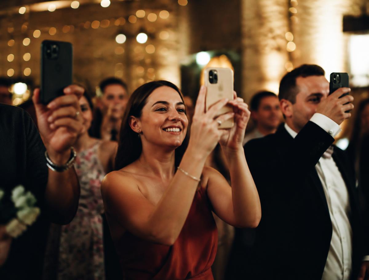 Guests holding up phones to capture moments at a celebration